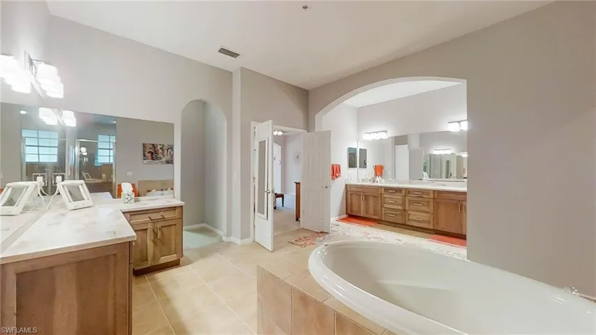 Bathroom featuring vanity, a relaxing tiled tub, and tile patterned floors