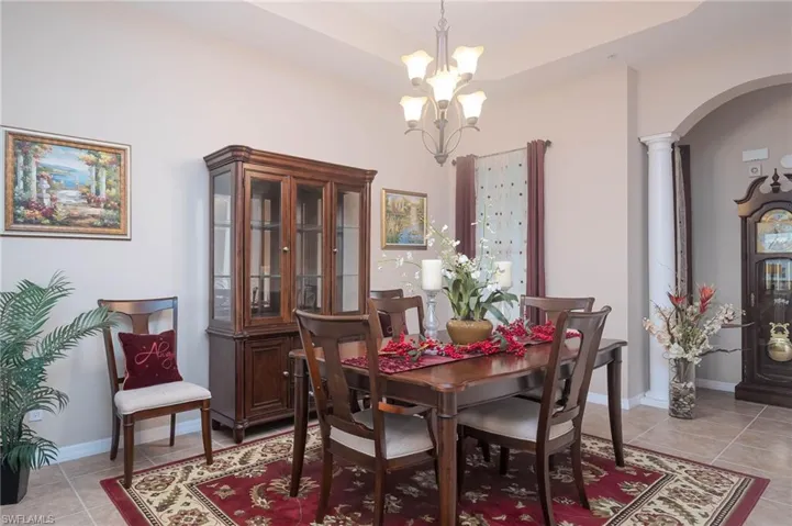Tiled dining space with ornate columns and an inviting chandelier