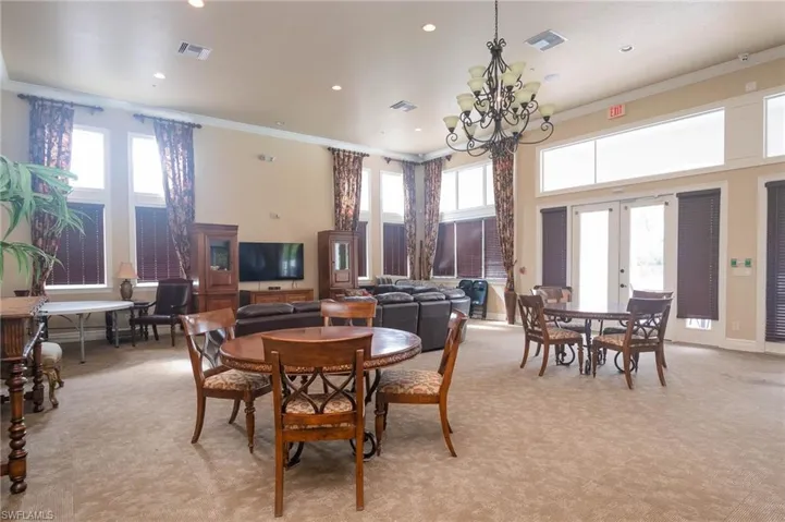 Carpeted dining space featuring ornamental molding, french doors, a wealth of natural light, and an inviting chandelier