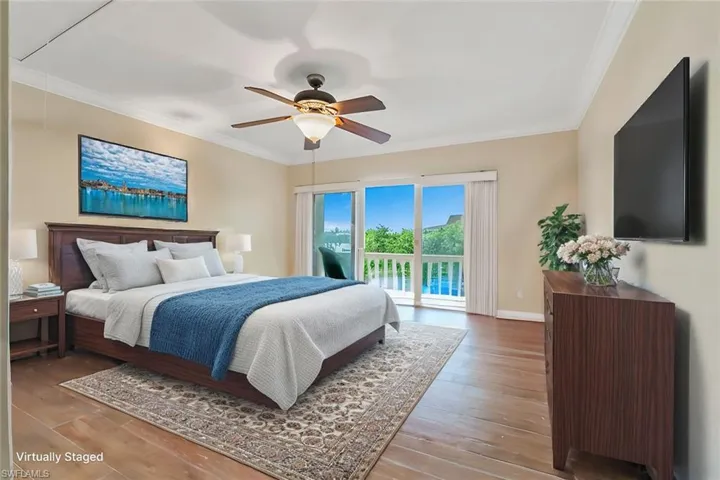 Bedroom featuring access to outside, ornamental molding, wood finished floors, ceiling fan, and attic access
