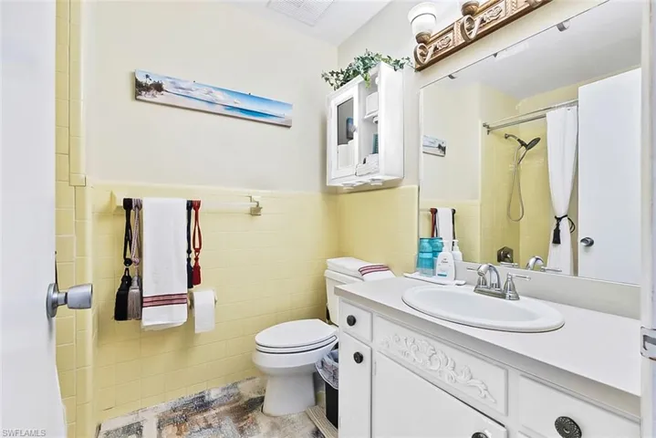 Bathroom featuring tile walls, curtained shower, vanity, toilet, and tile patterned floors