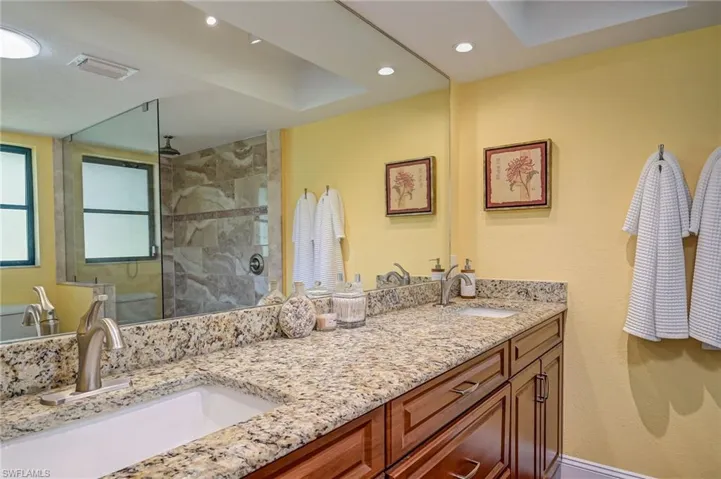 Bathroom with a walk in shower, double vanity, and recessed lighting