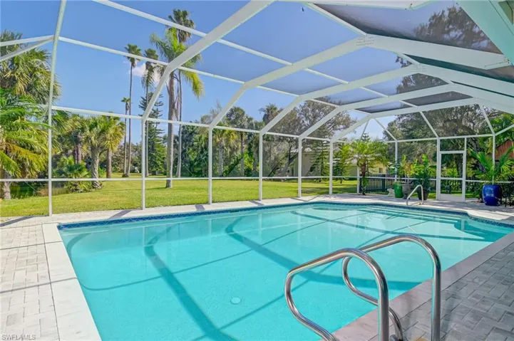 Swimming pool with a patio, a sunroom, a lanai, and a lawn