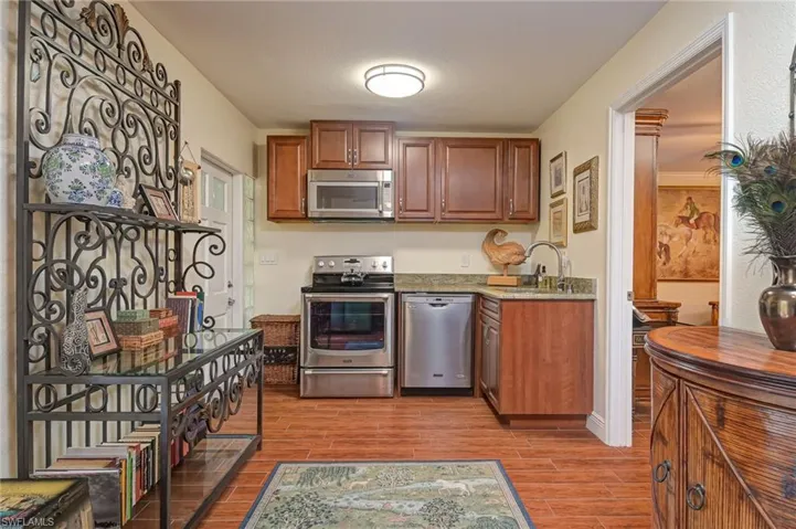 Separate in law suite kitchen with stainless steel appliances, tiled floors, light stone counters, and wood finish cabinets