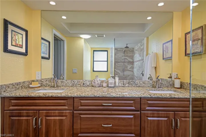 Bathroom featuring double vanity, a stall shower, a textured wall, and recessed lighting