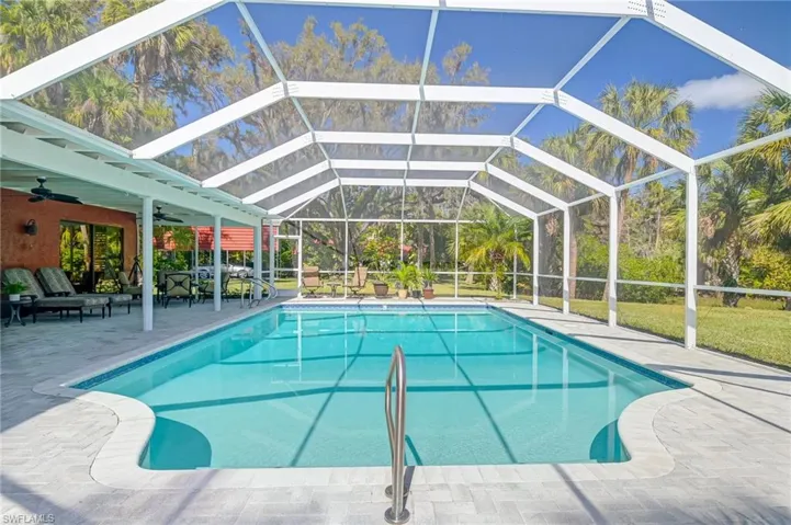 Outdoor pool with a patio area, glass enclosure, and a sunroom