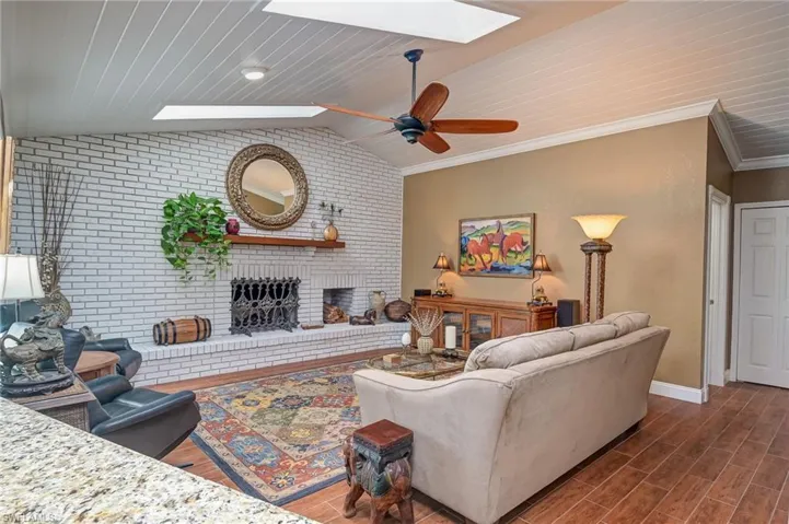 Living room with brick wall wood burning fireplace, wood lofted ceiling with a skylight