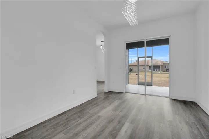 Unfurnished room featuring arched walkways and light wood-type flooring