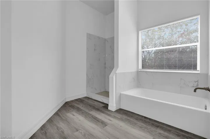 Bathroom with a bath, a marble finish shower, and light wood-type flooring