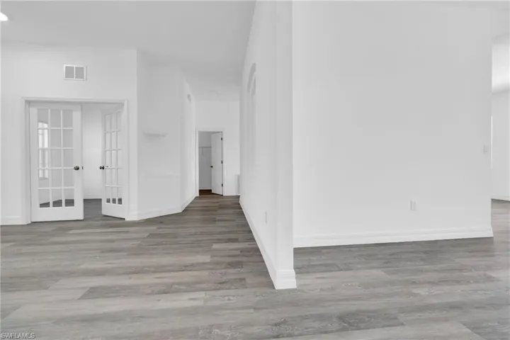 Empty room with french doors, light wood finished floors, and recessed lighting