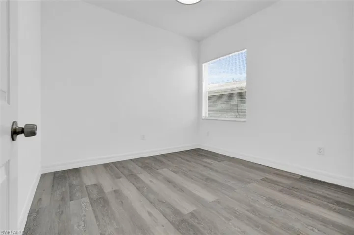 Spare room featuring light wood-style flooring and baseboards