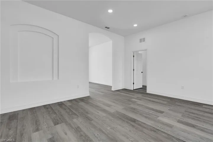 Unfurnished room with arched walkways, light wood-type flooring, and recessed lighting