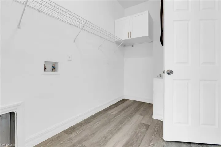 Laundry room featuring light wood-style flooring, cabinet space, and washer hookup
