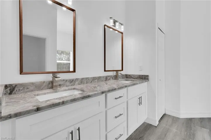 Full bathroom featuring double vanity and light wood-style flooring