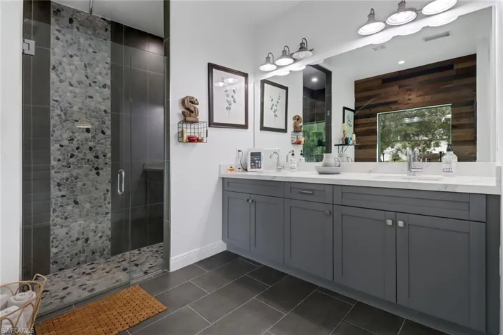 Bathroom with a shower with shower door, tile patterned floors, and double sink vanity