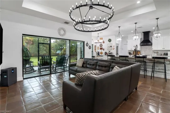 Tiled living room featuring a raised ceiling and a notable chandelier