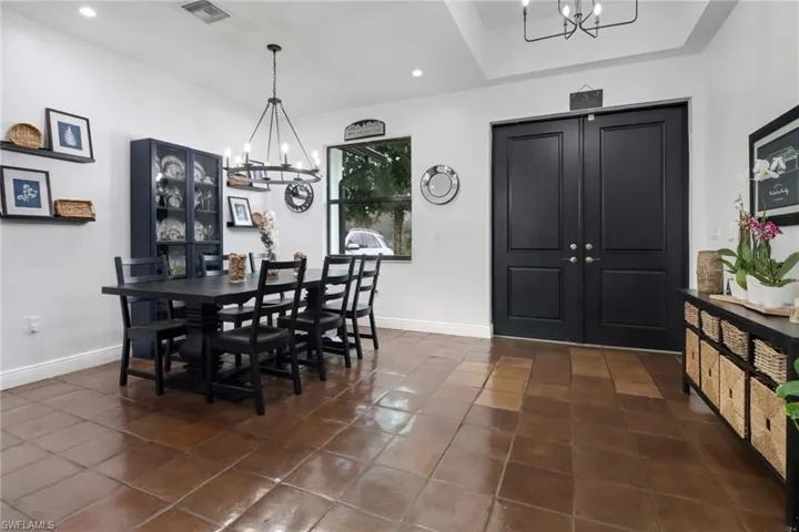 Dining space with dark tile patterned floors, a raised ceiling, and an inviting chandelier