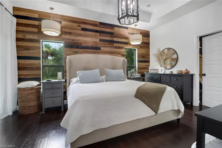 Bedroom featuring dark hardwood / wood-style floors, wooden walls, and a notable chandelier