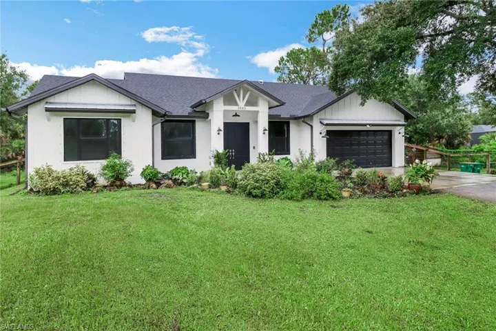 View of front of property featuring a garage and a front lawn
