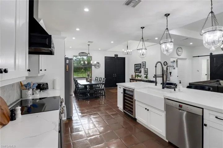 Kitchen featuring beverage cooler, a barn door, custom exhaust hood, hanging light fixtures, and appliances with stainless steel finishes