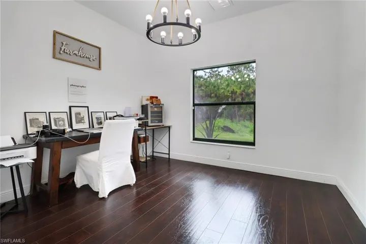 Office space featuring a chandelier and dark hardwood / wood-style floors