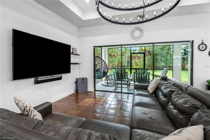 Living room featuring a chandelier, a raised ceiling, and tile patterned floors