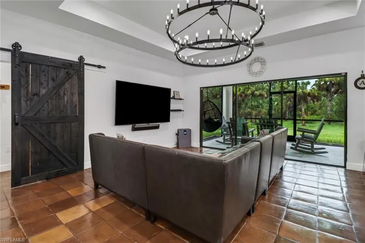 Tiled living room featuring a wealth of natural light, a raised ceiling, and a barn door
