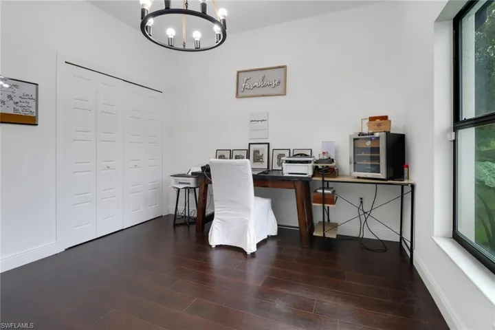 Office space featuring dark wood-type flooring and a chandelier