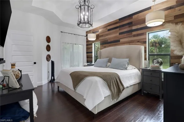 Bedroom featuring a notable chandelier, dark hardwood / wood-style flooring, and wooden walls