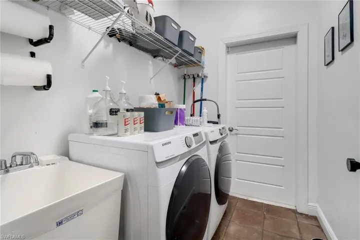 Washroom featuring sink, washing machine and dryer, and dark tile patterned flooring