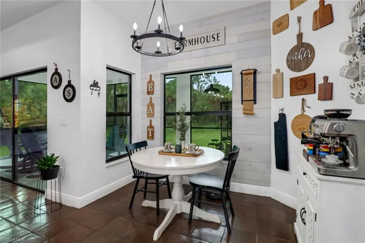 Tiled dining space featuring vaulted ceiling and a chandelier
