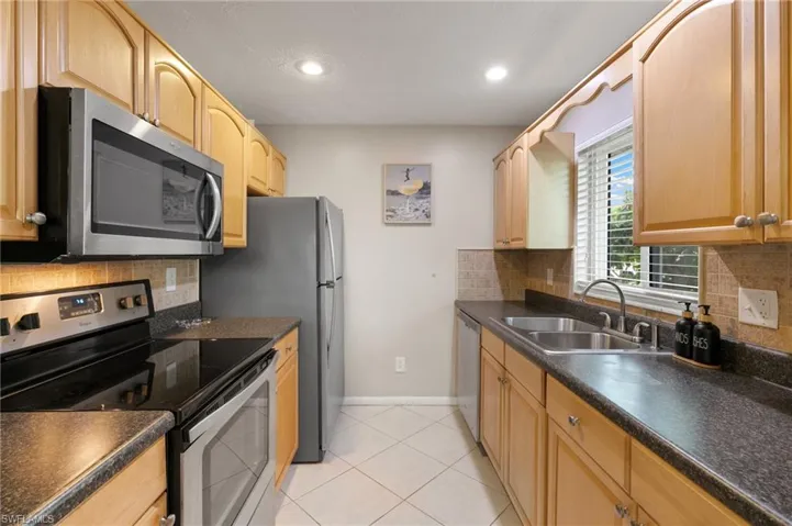 Kitchen with stainless steel appliances, backsplash, dark countertops, and recessed lighting