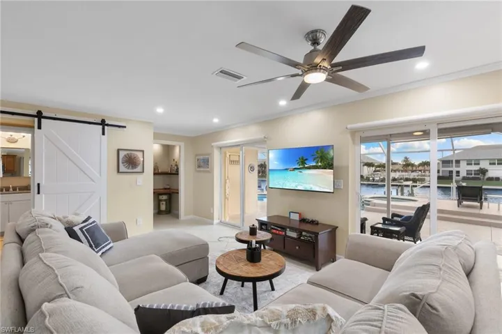 Tiled living area featuring ornamental molding, a barn door, recessed lighting, and a ceiling fan