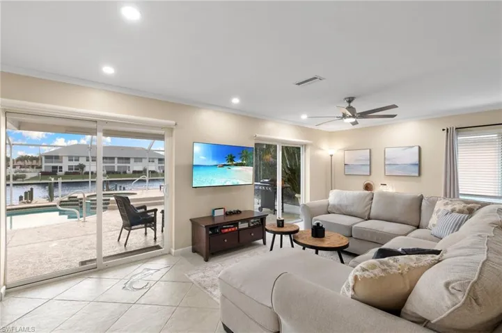 Living room featuring tile patterned flooring, ornamental molding, a ceiling fan, recessed lighting, and a sunroom