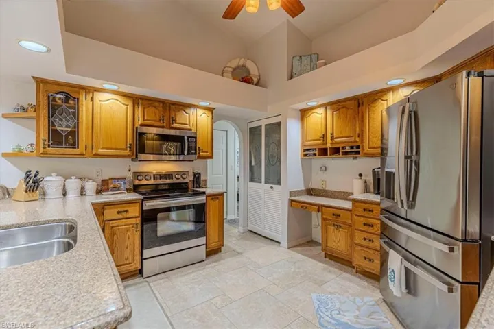 Kitchen with stainless steel appliances, open shelves, recessed lighting, arched walkways, and wood finish cabinets