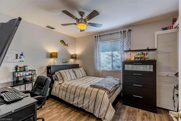 Bedroom with an office area, wood finished floors, a ceiling fan, and a closet