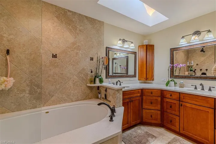 Full bathroom featuring a skylight, double vanity, and a garden tub