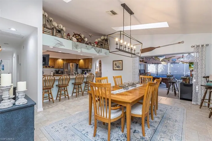 Dining room featuring stone tile floors, a skylight, a chandelier, and lofted ceiling