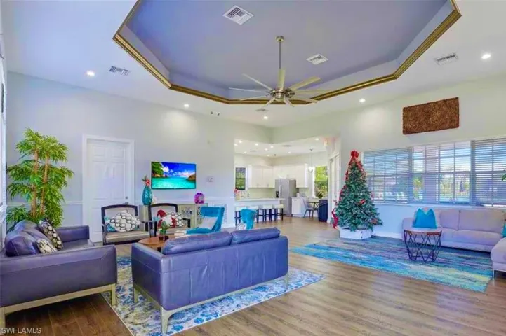 Living area with a raised ceiling, a ceiling fan, recessed lighting, and visible vents