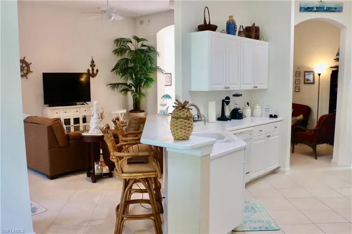 Kitchen featuring arched walkways, a kitchen breakfast bar, light tile patterned flooring, and light countertops