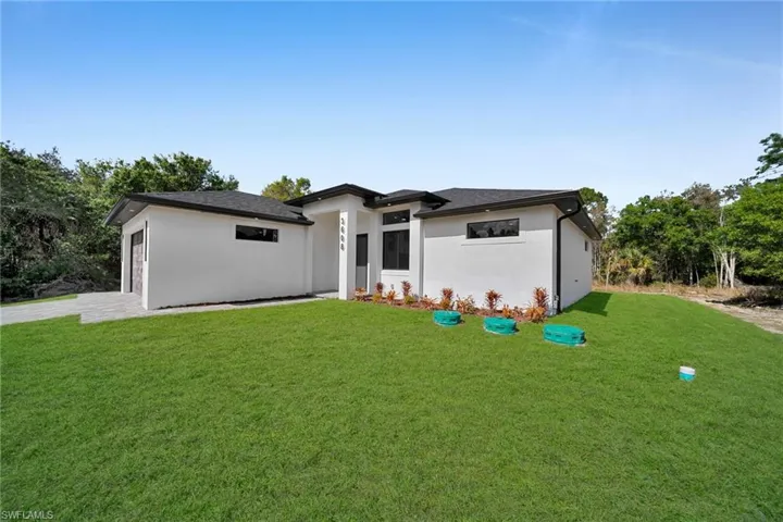 Prairie-style home featuring a front lawn, stucco siding, and driveway