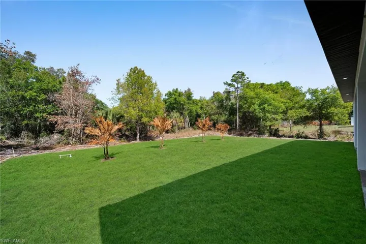 View of grassy yard featuring view of scattered trees