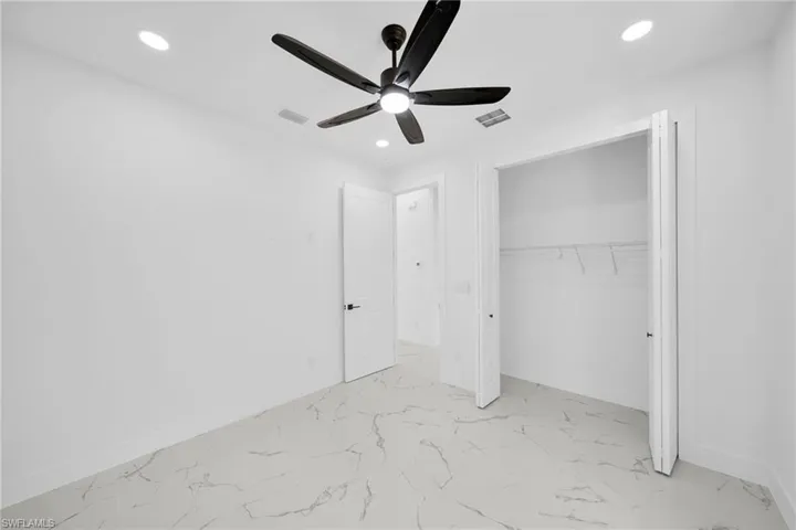 Unfurnished bedroom with ceiling fan, light marble finish floors, a closet, and recessed lighting