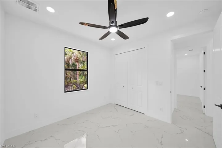 Unfurnished bedroom featuring light marble finish flooring, recessed lighting, a closet, and a ceiling fan