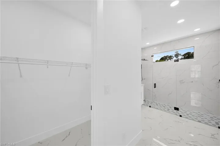 Full bathroom with a walk in closet, a marble finish shower, recessed lighting, and light marble finish floors