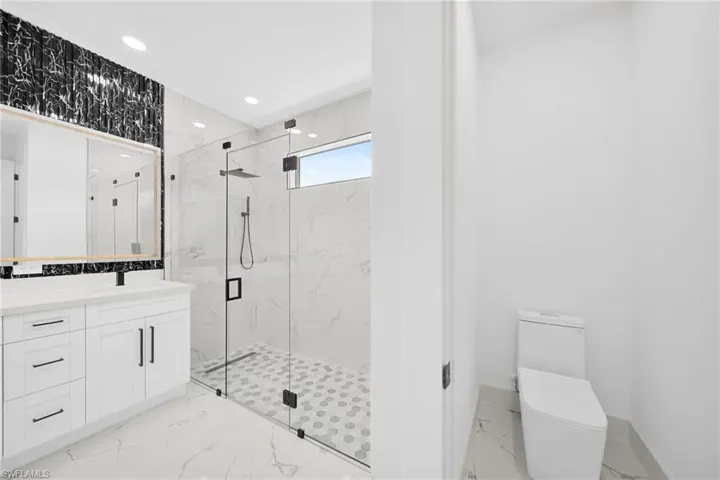 Full bathroom with light marble finish flooring, a marble finish shower, vanity, and recessed lighting