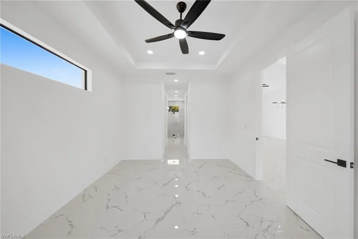 Spare room featuring recessed lighting, a ceiling fan, a tray ceiling, and light marble finish floors