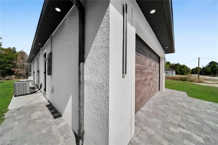 View of side of home with stucco siding, a garage, and a yard