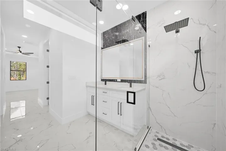 Full bath with light marble finish flooring, double vanity, a marble finish shower, recessed lighting, and a ceiling fan