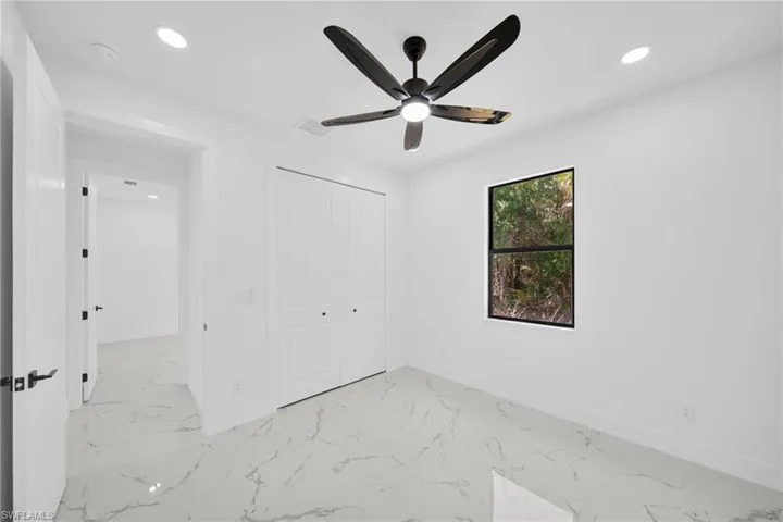 Unfurnished bedroom with recessed lighting, light marble finish flooring, a closet, and a ceiling fan